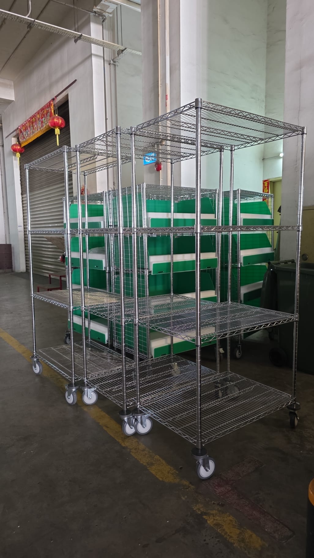 Chrome wire storage shelving units holding green plastic bins in Singapore warehouse